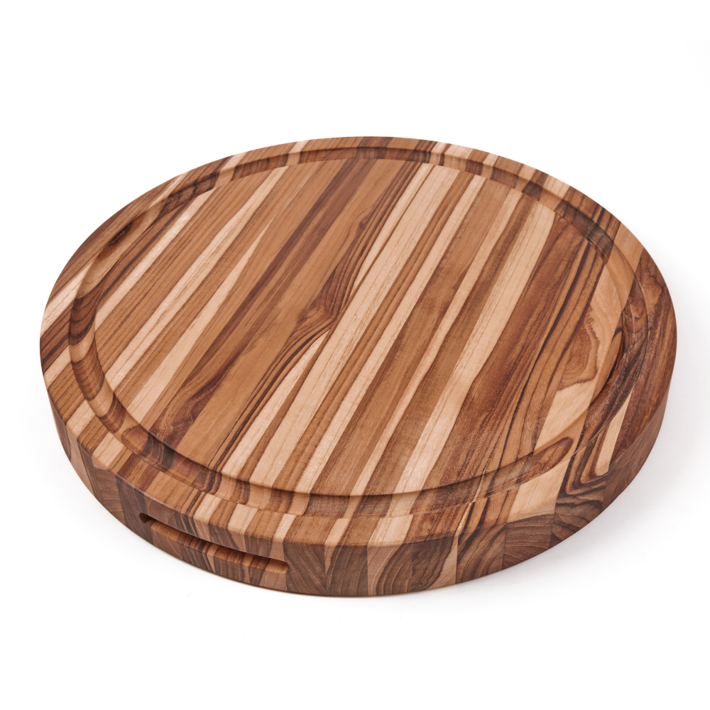 Traditional round teakwood carving board featuring natural edge grain and a perimeter juice groove.