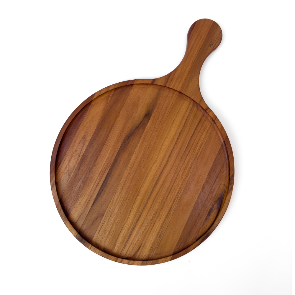 Round edge grain teakwood serving board with a paddle handle and natural wood grain on a white background.