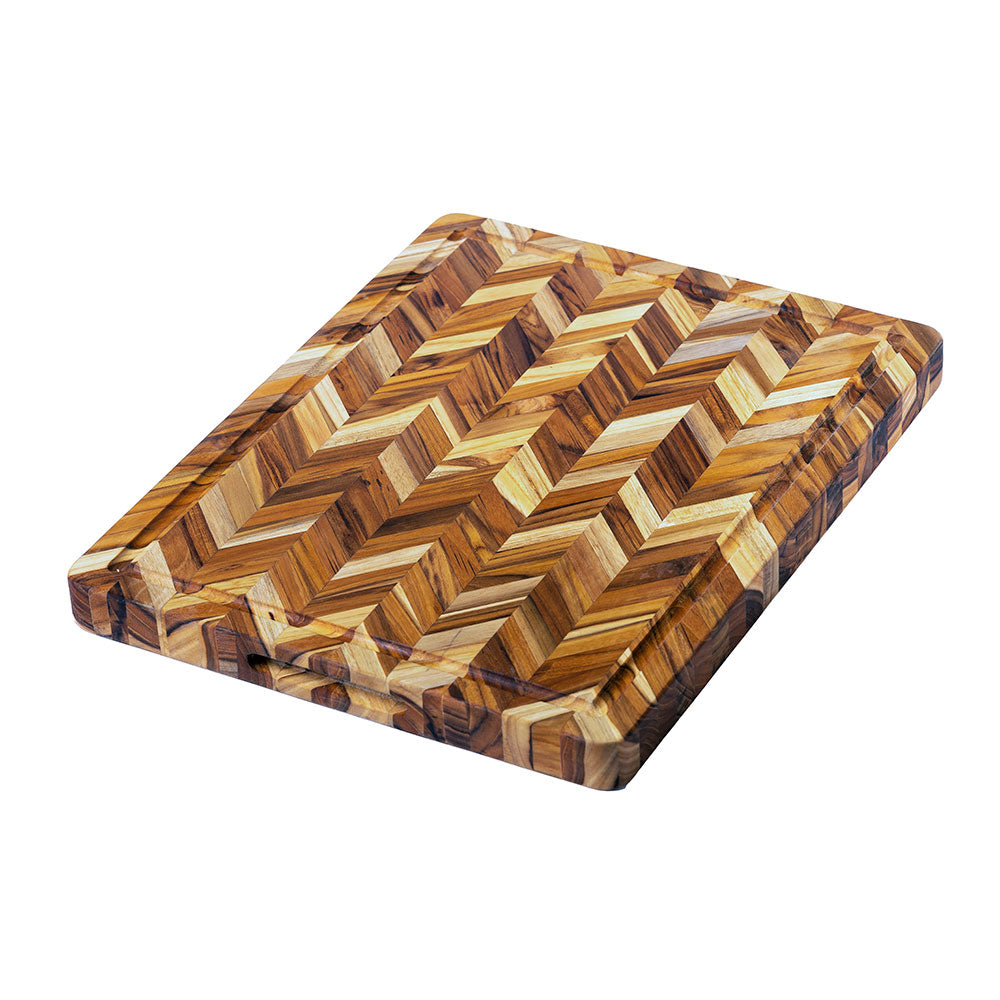 Large teak wood cutting board with a herringbone pattern, perimeter juice groove, and integrated side hand grips.