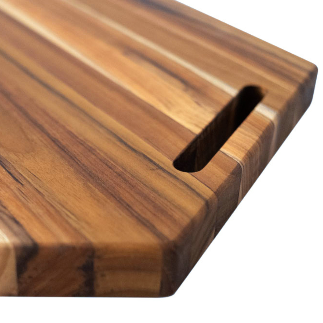 Close-up of a hexagonal teakwood cutting and serving board showcasing its natural wood grain and handle cutout.