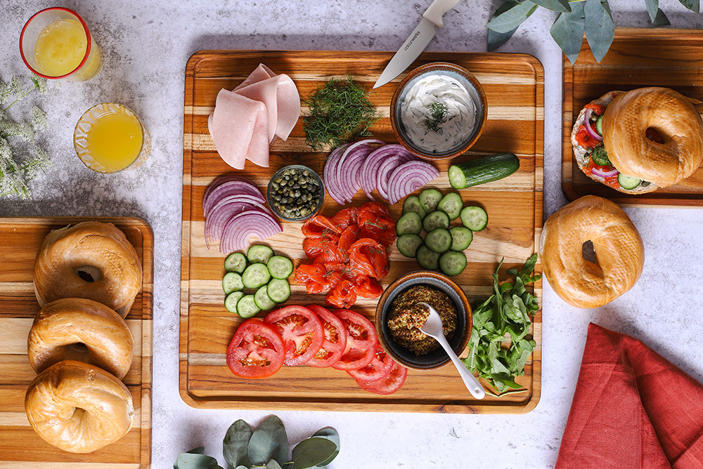 Square teakwood serving trays presented with bagels, smoked salmon, and fresh brunch toppings.