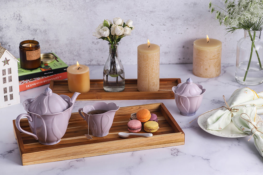 Teakwood nesting trays styled with a purple tea set and macarons on a marble tabletop.