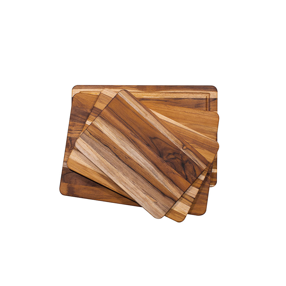 Stacked rectangular teakwood cutting boards in various sizes featuring natural edge grain and rounded edges.