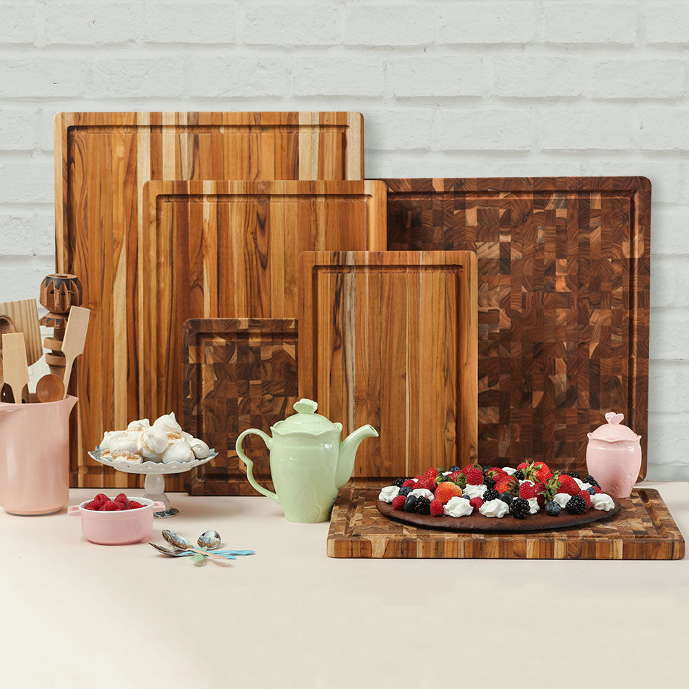 Teakhaus teak wood end grain and edge grain cutting boards styled with a green teapot and fresh berry dessert.